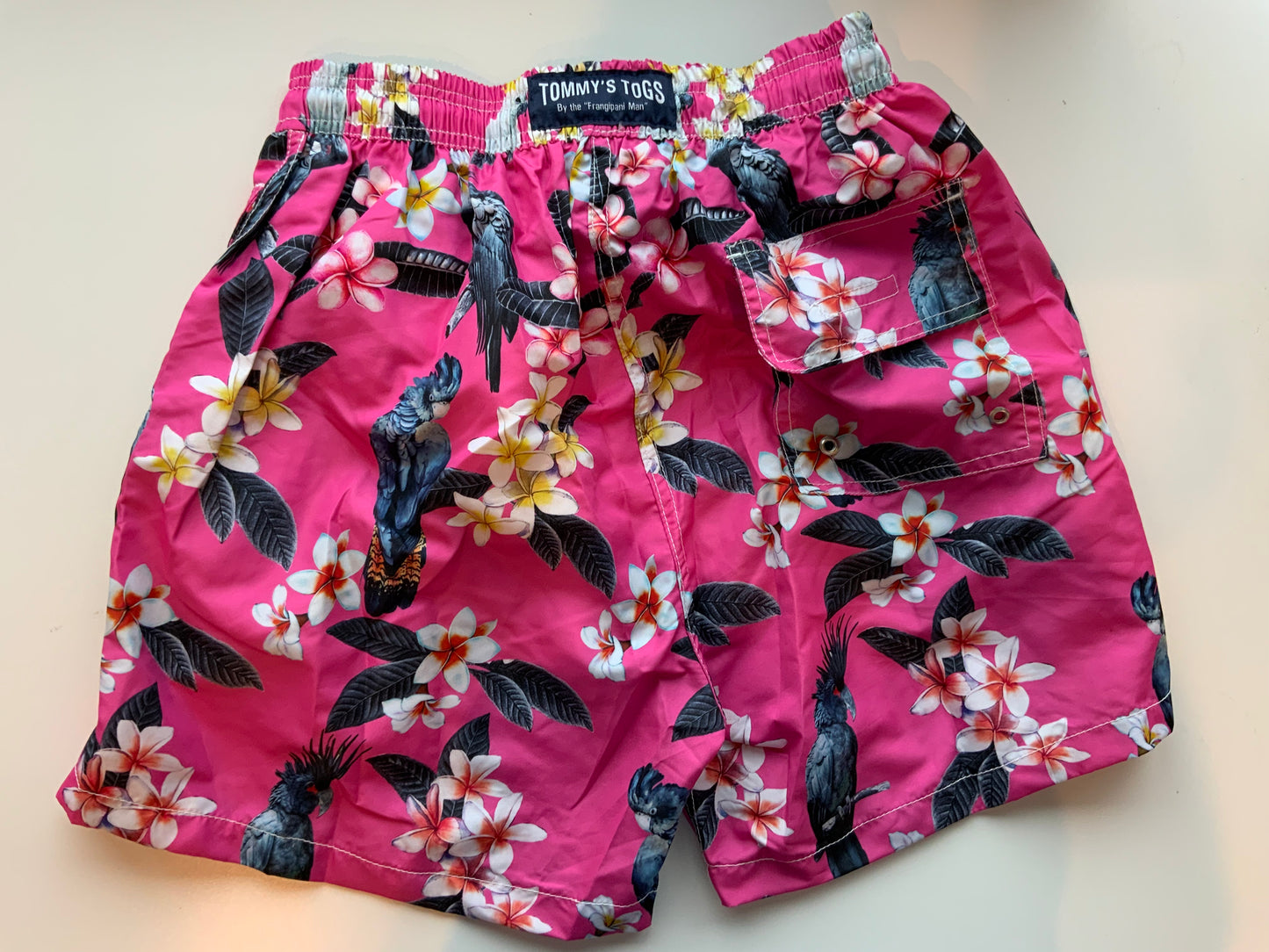 Black cockatoo, frangipani, pink shorts
