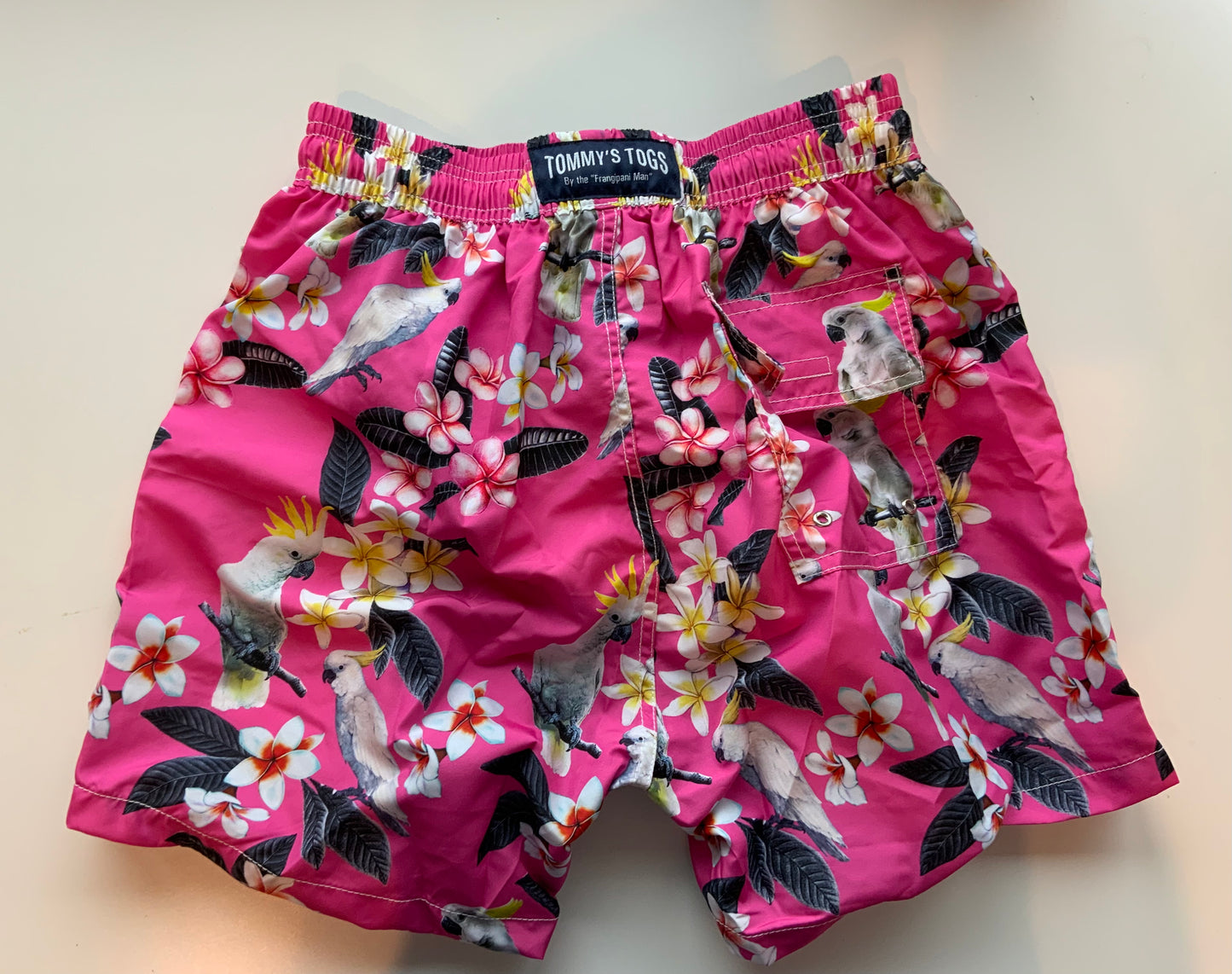 White cockatoo, frangipani, pink shorts